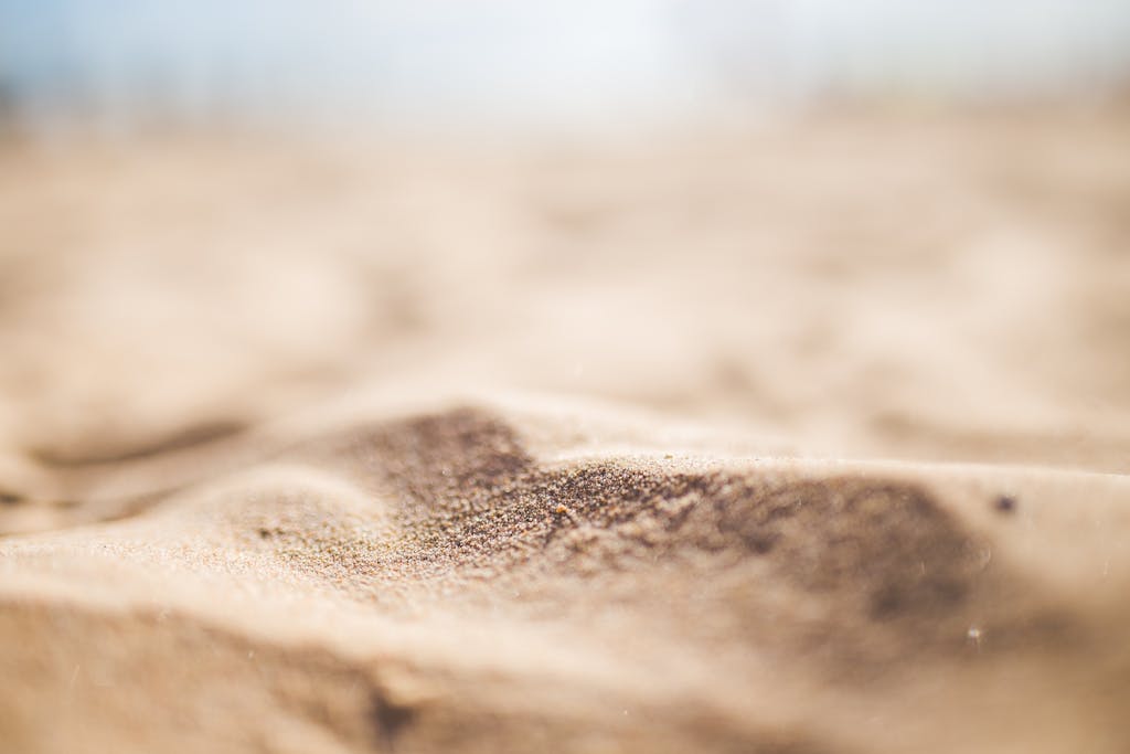 A detailed macro shot highlighting the texture and color of sandy dunes at a beach.